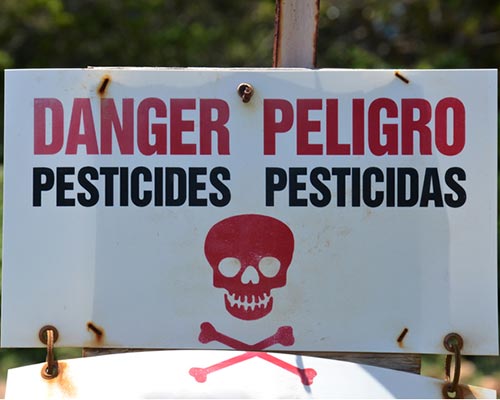 Sign warning of dangerous pesticides in English and Spanish